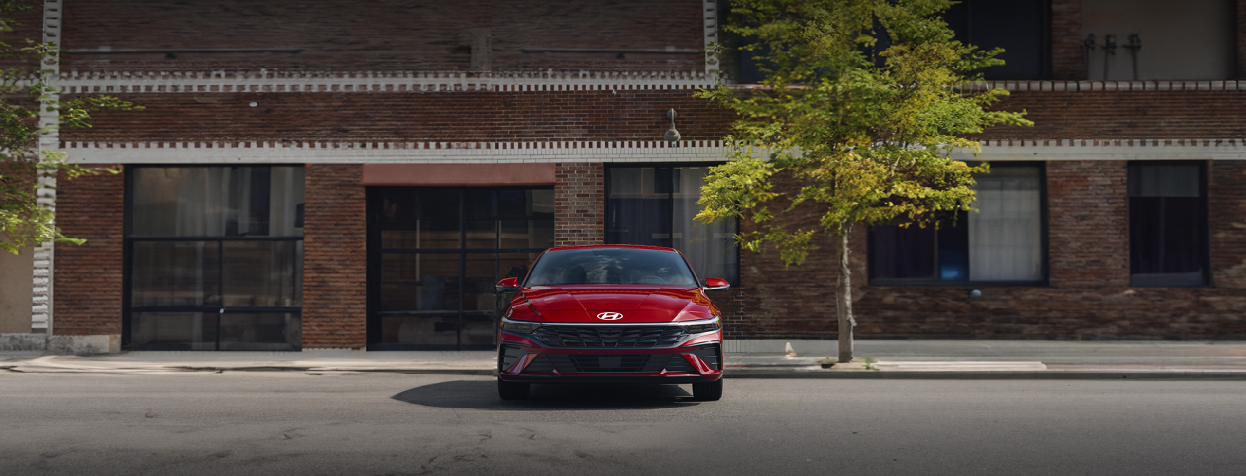 Vista frontal del nuevo Elantra 2026, en color rojo, estacionado en la calle