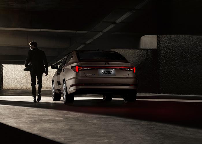 Hombre caminando junto a Hyundai HB20 Sedán en un estacionamiento