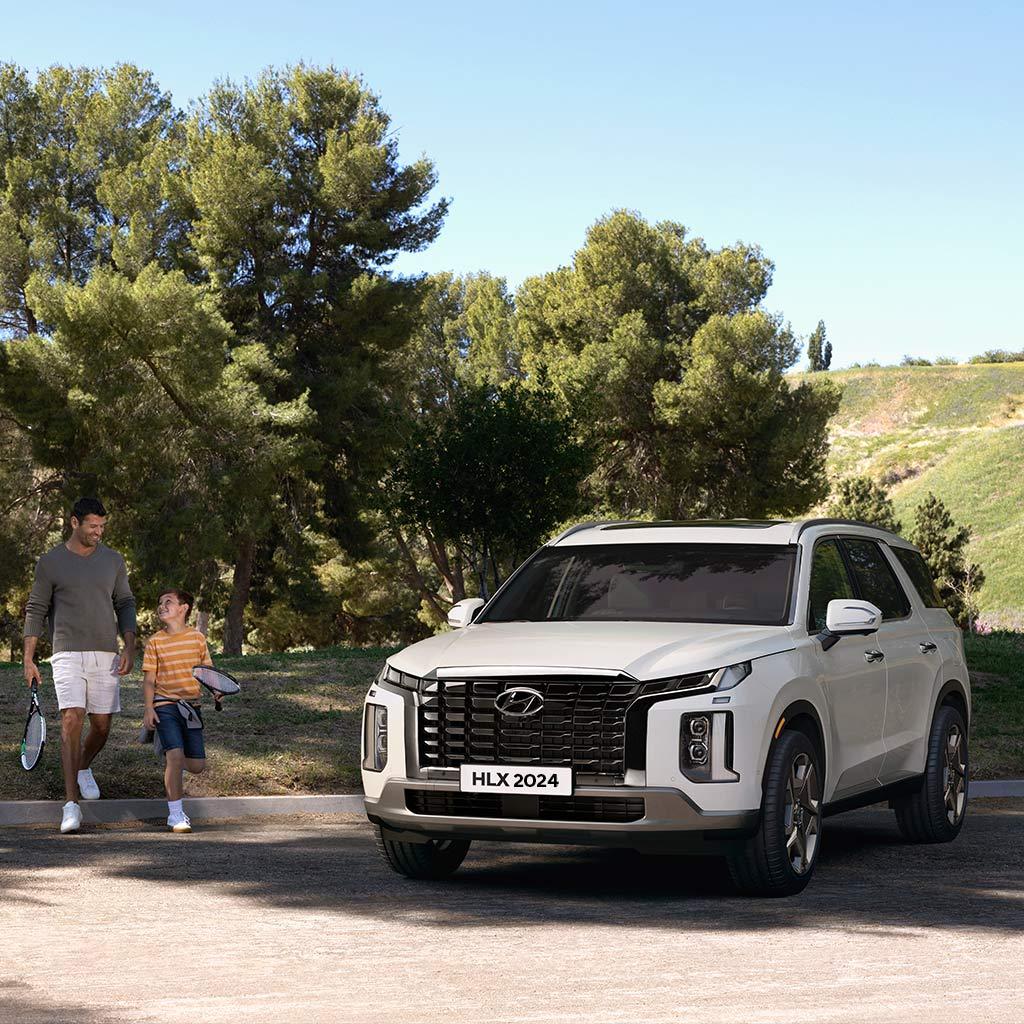 Familia caminando hacia una Hyundai Palisade color blanca en un parque